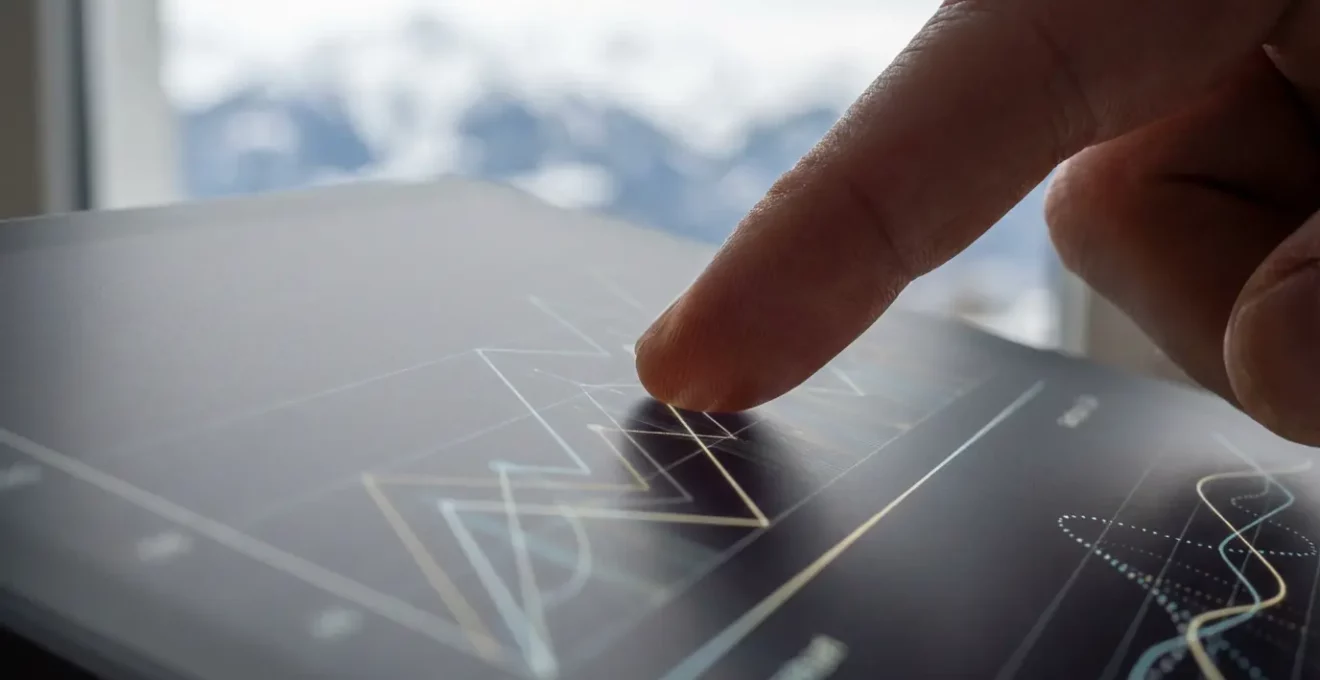 Main pointant un graphique de rentabilité sur tablette avec montagne en arrière-plan flou