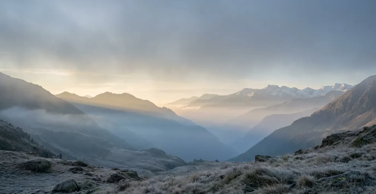 Vallée pyrénéenne isolée baignée dans la brume matinale avec sommets enneigés au loin